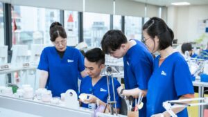 People in blue scrubs working on dental prosthetics in a lab.
