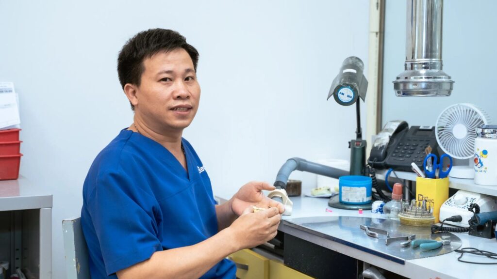 A person works on a dental prosthesis at a lab bench.