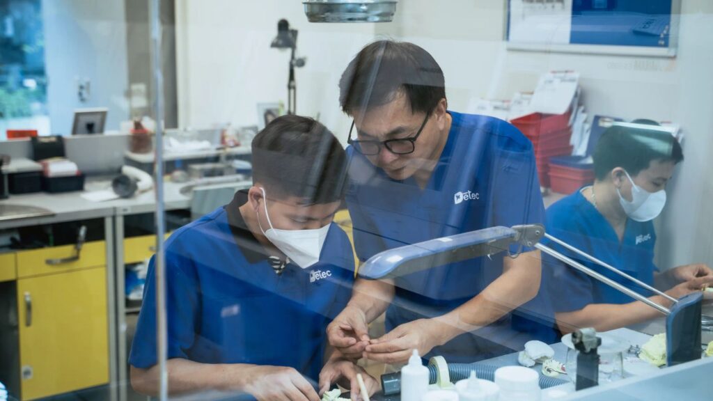 People working in a dental laboratory with tools and equipment.