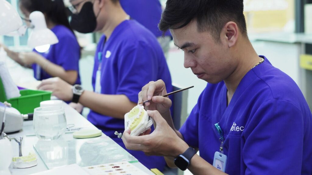 A person works on a dental mold with tools in a laboratory.