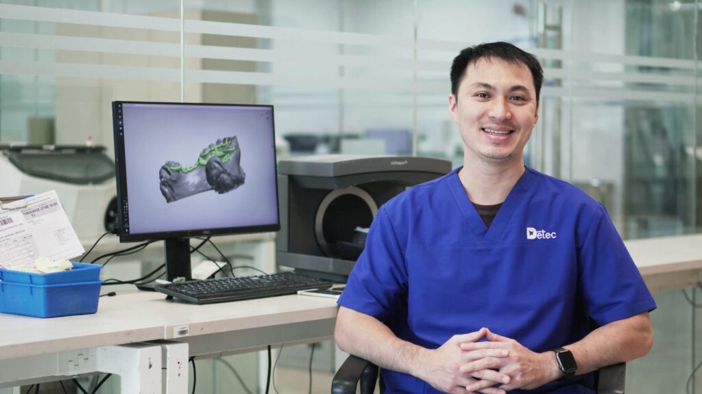 A person in a dental lab with a 3D scanner and computer.