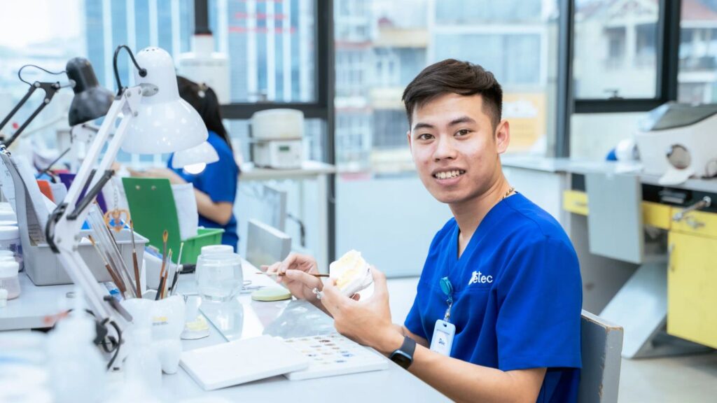 A person works on a dental prosthesis in a laboratory setting.